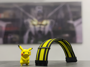 Yellow Pikachu toy next to a black and yellow cable on a blurred background