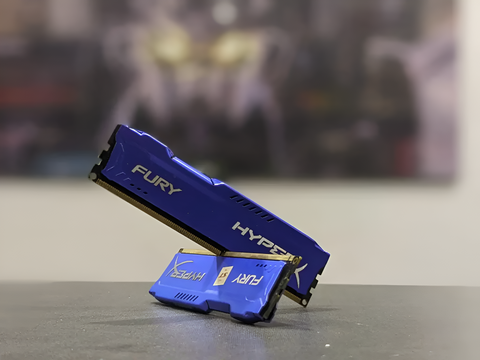 Blue HyperX FURY RAM sticks on a gray surface with a blurred background