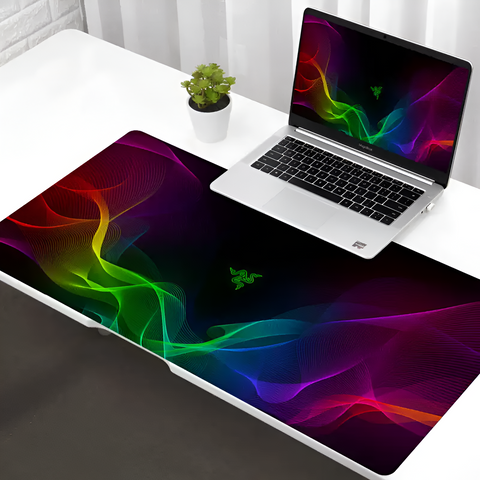 Laptop on a colorful desk mat with Razer logo on a white surface.