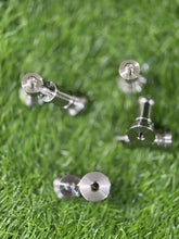 Silver stud earrings on a grassy background
