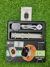 YAX smart watch packaging with watch, charger, and manual on grass