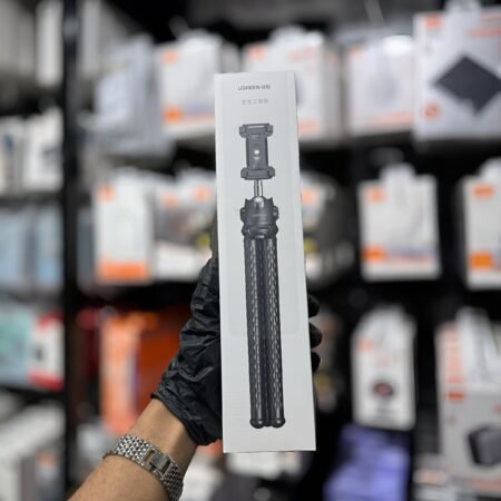 Hand holding a box with a tripod on a blurred store shelf background