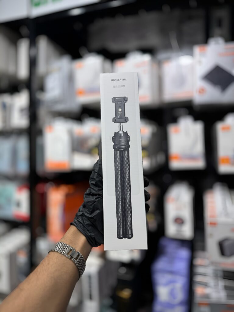 Hand holding a box with a tripod on a blurred store shelf background